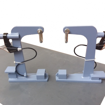 Un paio di morsetti da palestra blu con maniglie e leve nere sono visualizzati su una superficie piana. Ogni attrezzatura personalizzata presenta un bullone nella parte superiore, un meccanismo di bloccaggio curvo e un filo a spirale fissato al manico. Sono posizionati simmetricamente, uno di fronte all'altro.